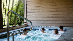A hot tub with four people, metal railings, and a wooden wall. - Tall Chief RV & Camping Resort (Fall City)