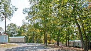A campground with multiple mobile homes, a gravel parking area, and trees providing shade. - Hidden Cove RV Resort (Arley)