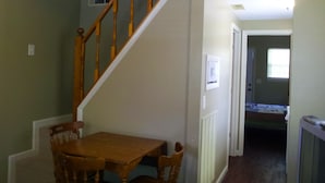 A dining area with a wooden table and chairs, a staircase, and a hallway leading to another room. - Hidden Cove RV Resort (Arley)