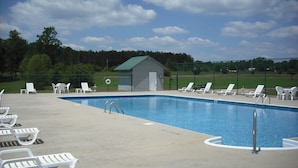 A swimming pool with lounge chairs and a small shed. - Hidden Cove RV Resort (Arley)