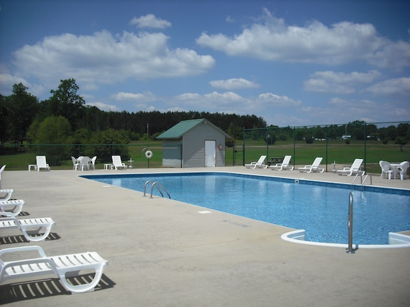 A swimming pool with lounge chairs and a small shed. - Hidden Cove RV Resort (Arley)
