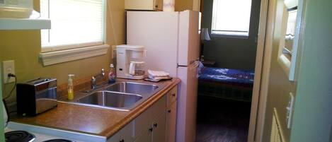 A compact kitchen with a stove, sink, and refrigerator.