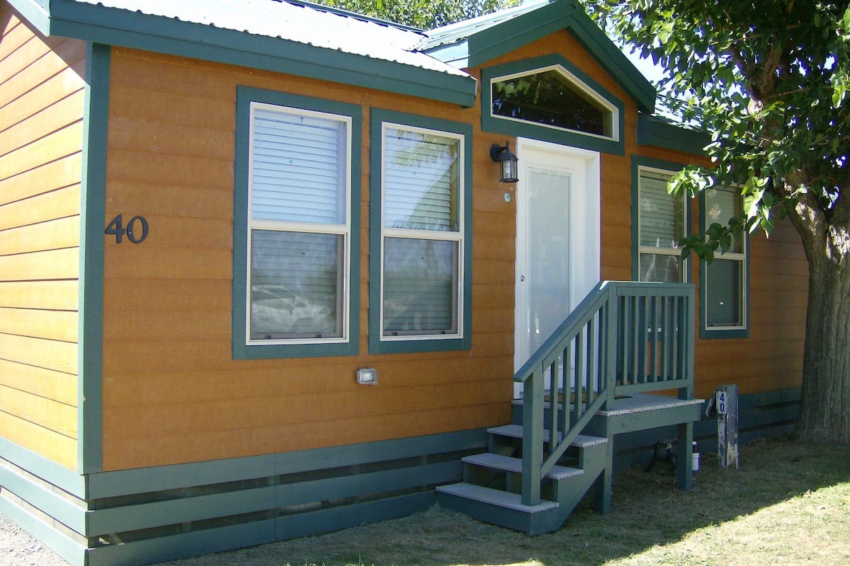 A small, single-story wooden building with a porch and a set of stairs leading to the entrance.