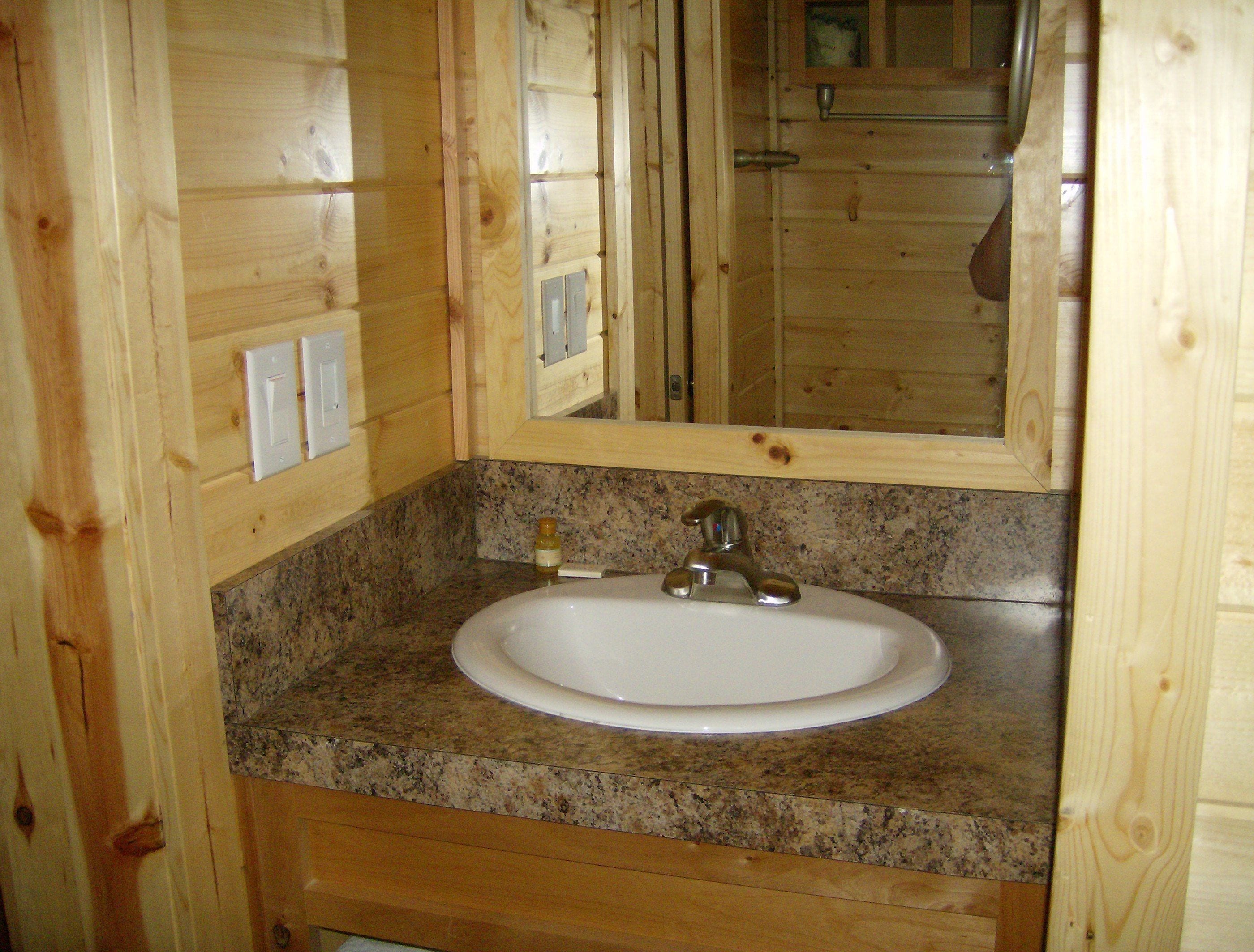 A wooden bathroom with a granite countertop, a white sink, and a mirror.
