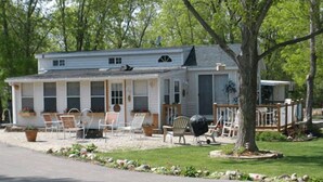 A single-story house with a porch, outdoor seating, and a barbecue grill. - Lakeland RV Campground (Milton)