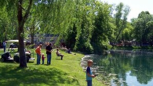 A lakeside area with people fishing and a golf cart nearby. - Lakeland RV Campground (Milton)