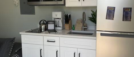 Een moderne keuken met witte kasten, een roestvrijstalen koelkast, een magnetron en een koffiezetapparaat.
