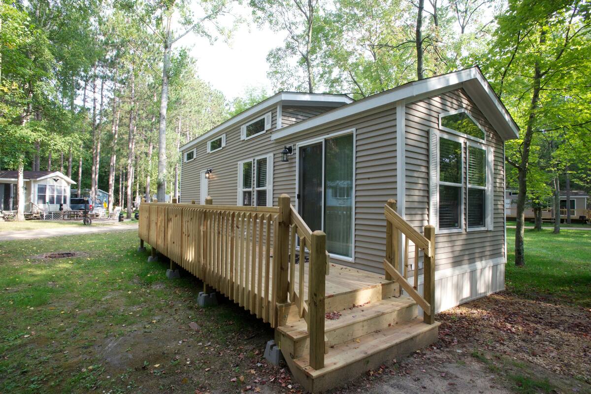 A small, single-story cabin with a wooden deck and a staircase leading to the entrance.