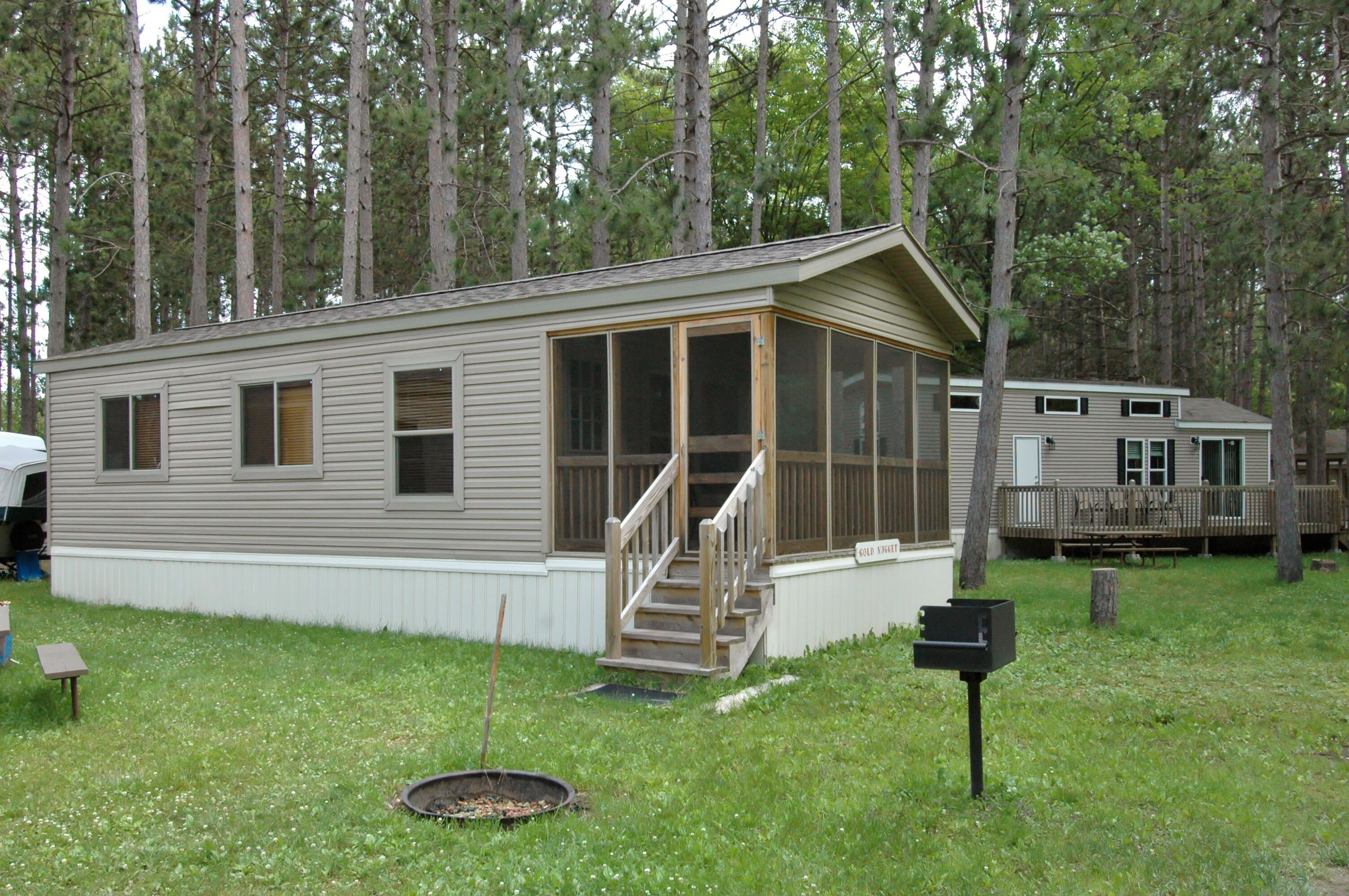 A mobile home with a covered porch and a small front yard.