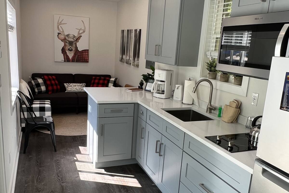 A modern kitchen with grey cabinets, a built-in microwave, and a central island with a sink.