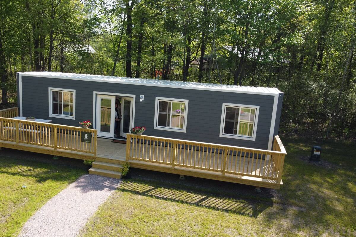 A two-story cabin with a covered porch, a front door, and windows.