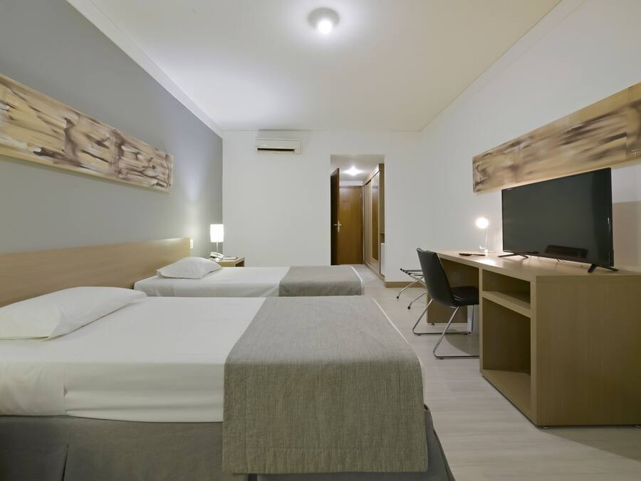 Een hotelkamer met twee bedden, een bureau, een stoel en een televisie.