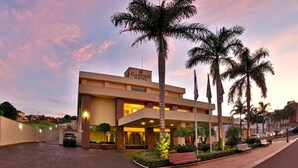 A modern hotel with a prominent entrance, palm trees, and a well-lit driveway. - Garden Hotel (Ribeirão Preto)