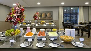 A buffet with various food items and a floral centerpiece. - Garden Hotel (Ribeirão Preto)