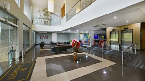 A spacious lobby with a reception desk, a seating area, and a decorative vase with flowers. - Garden Hotel (Ribeirão Preto)
