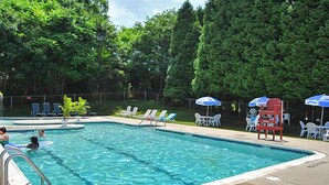 A swimming pool with a no diving sign, surrounded by lounge chairs and umbrellas.