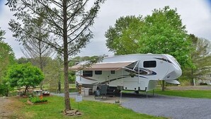 A recreational vehicle (RV) parked in a grassy area with a picnic table and a small garden.