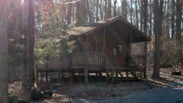 A cabin with a deck and a porch, surrounded by trees.