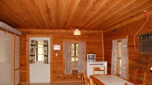 A wooden cabin interior with a dining table, chairs, a television, and a refrigerator. - Cherokee Landing Campground (Saulsbury)