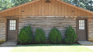A rustic log cabin with two doors and a central window.
