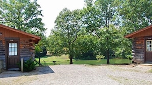 A rustic cabin-style building with a gravel driveway and a large tree in the center. - Cherokee Landing Campground (Saulsbury)