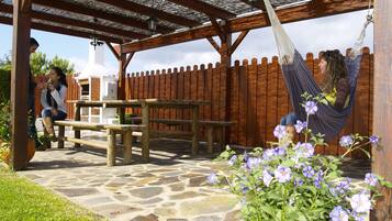An outdoor patio with a wooden pergola, stone flooring, and a hammock.