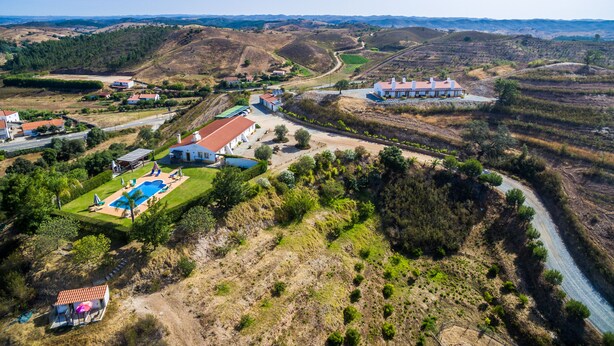 An aerial view of a rural property with multiple buildings, a swimming pool, and a river. - Nave Redonda do Cerro (Odemira)