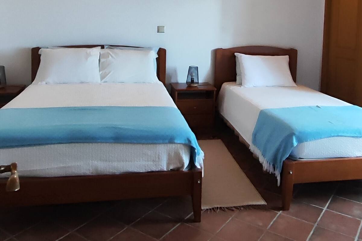 A room with two wooden beds, a tiled floor, and a sloped ceiling with wooden beams.