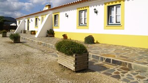 A yellow and white building with a tiled roof and stone steps leading to the entrance. - Nave Redonda do Cerro (Odemira)