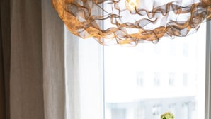 Une table avec un vase de fleurs blanches, un verre de café glacé et un magazine.