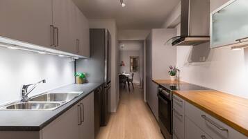 Una cocina moderna con electrodomésticos de acero inoxidable, encimera de madera y una isla central.