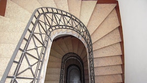 A spiral staircase with a metal railing and a stone wall.
