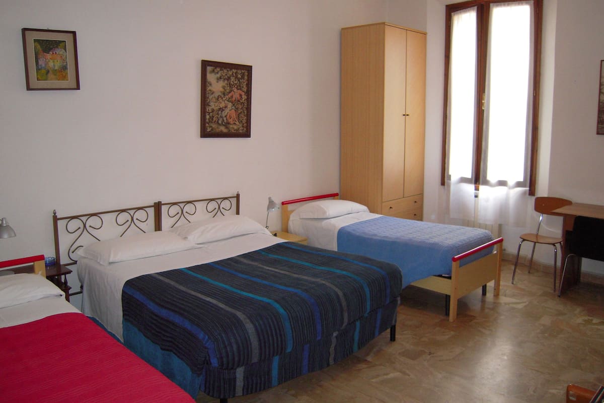 A bedroom with two beds, a wardrobe, a desk, and a chair.