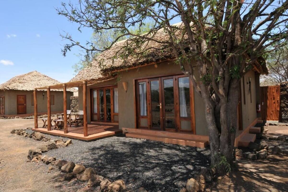 A rustic building with a thatched roof, large windows, and a wooden deck.