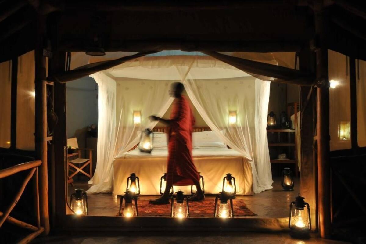 A room with a bed under a canopy, surrounded by lanterns, and a person in a red robe.