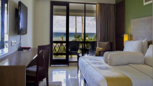Ein Hotelzimmer mit Bett, Schreibtisch und Fernseher. Ein Balkon bietet Blick aufs Meer.