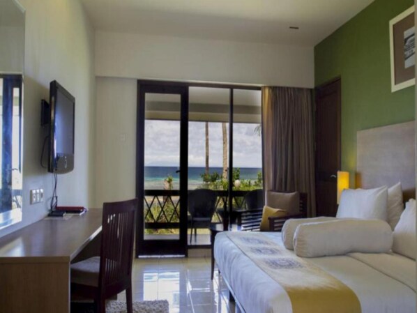 A hotel room with a bed, a desk, and a TV. There is a balcony with a view of the ocean. - Asana Biak Papua (Biak)