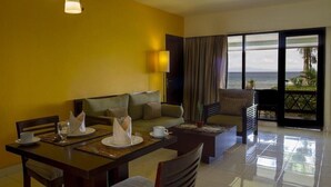 A hotel room with a dining area, a sofa, and a balcony with a view of the ocean. - Asana Biak Papua (Biak)