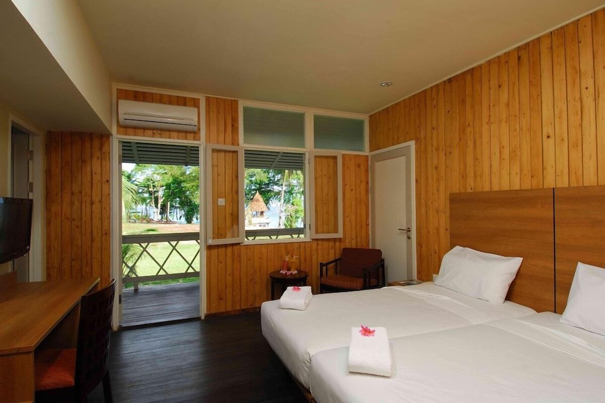 Une chambre d’hôtel avec un intérieur en bois, un lit avec du linge de maison blanc, un bureau avec une chaise et un téléviseur.