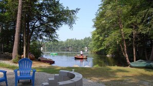 A lakeside seating area with a fire pit and two blue Adirondack chairs.