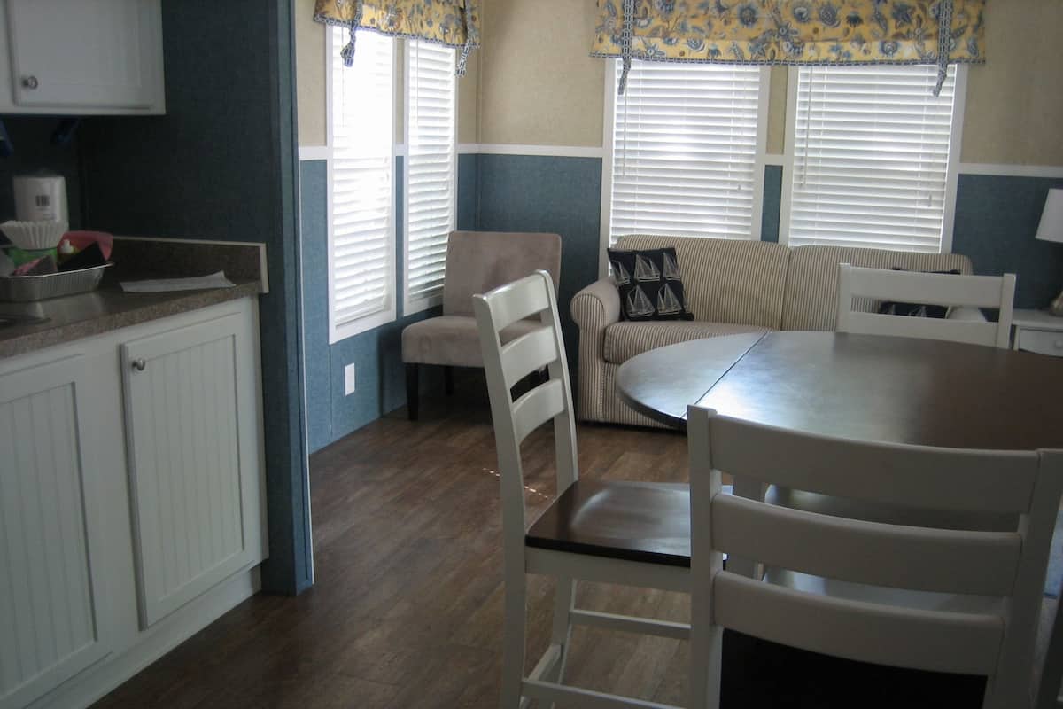 A kitchen with white cabinets, a dining table, and a sofa.