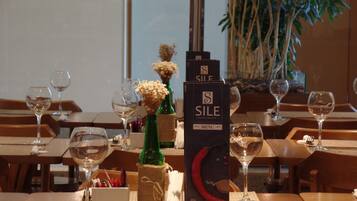 Un ambiente de restaurante con mesas dispuestas para comer, destacando copas de vino, menús y una botella de vino.