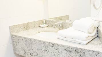 A bathroom with a granite countertop, two mirrors, a hairdryer, and a trash can.
