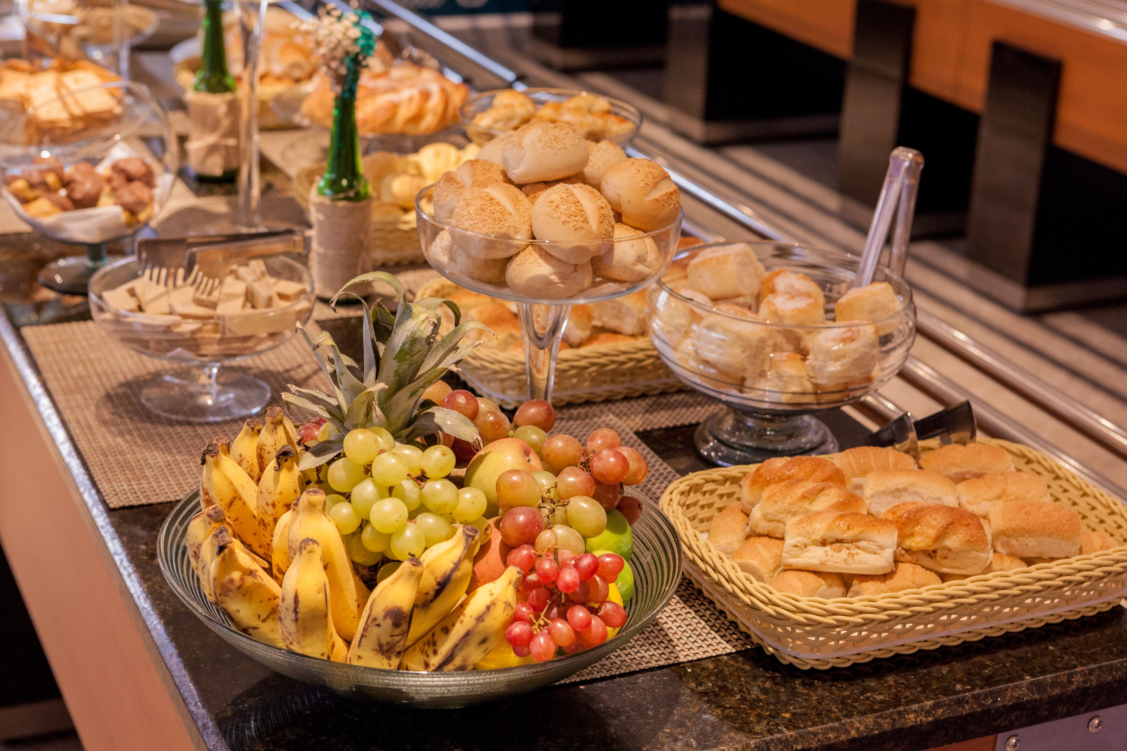 A buffet with various food items including fruits, bread, and pastries.