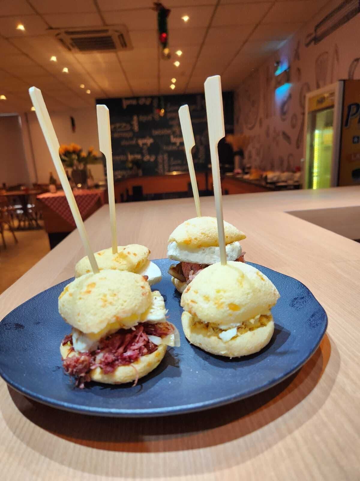 Ein Teller mit drei Sandwiches auf einem blauen Untersetzer, platziert auf einem Tisch in einem Restaurant.