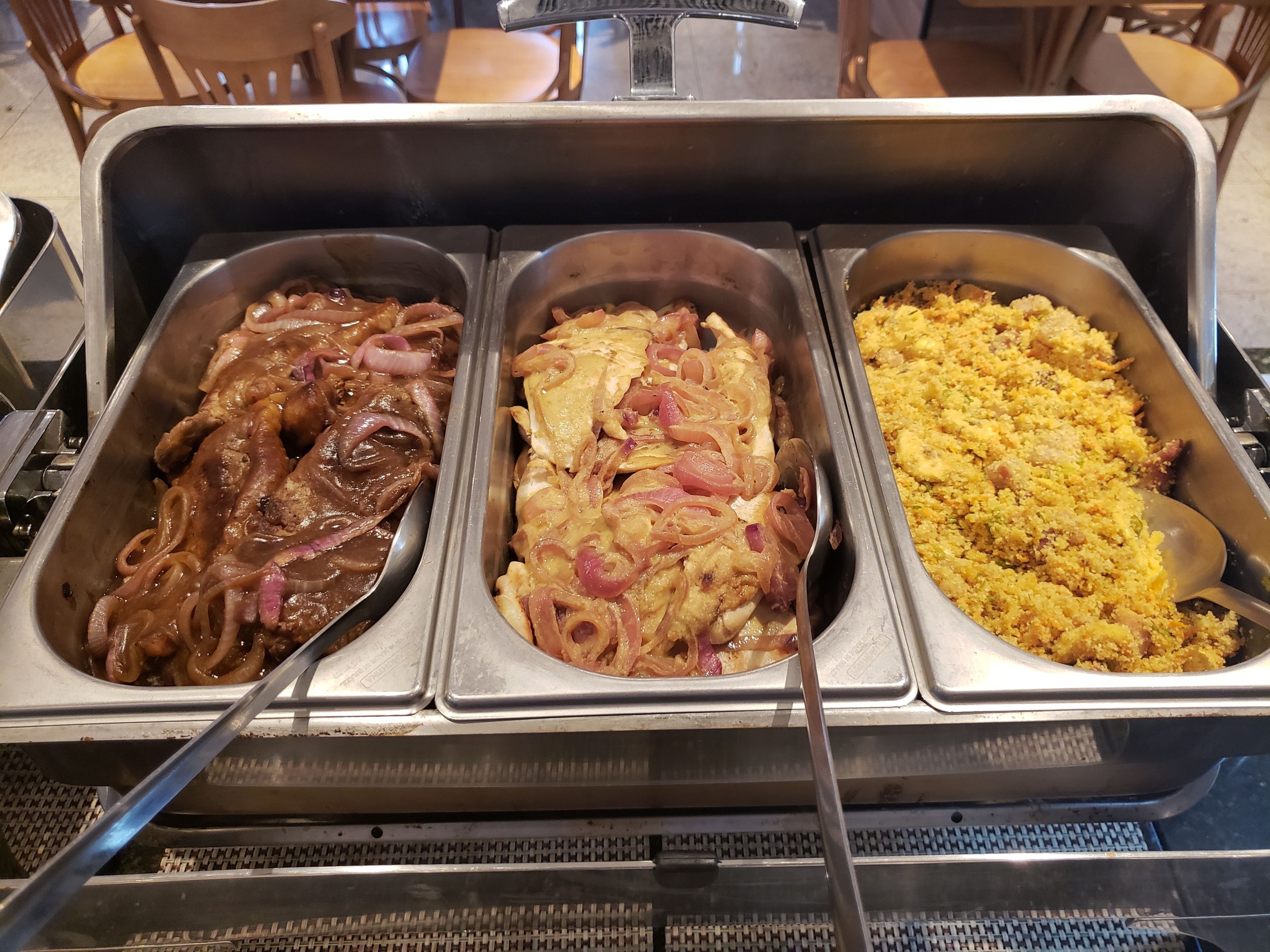 Een buffet met drie schalen eten: één met geglazuurd vlees, één met kip en uien, en één met een gele rijstgerecht.