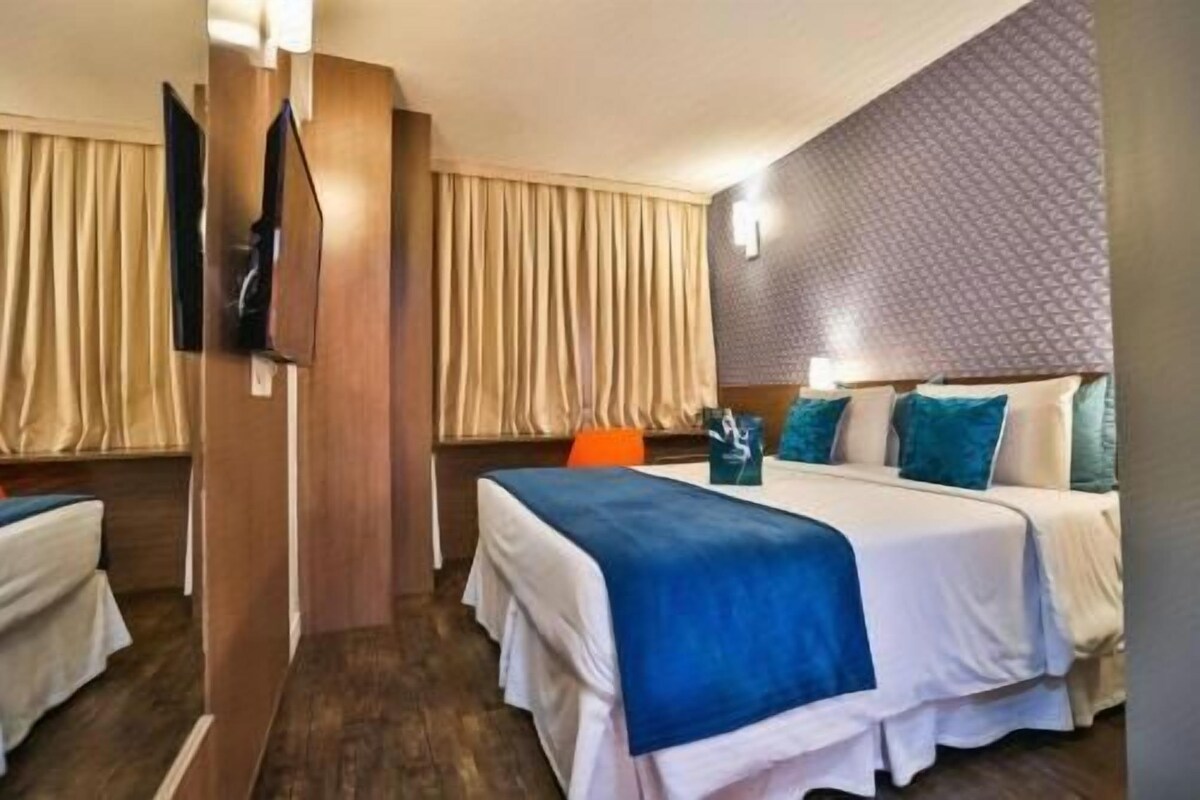 A hotel room with two beds, a TV, and a patterned wall.
