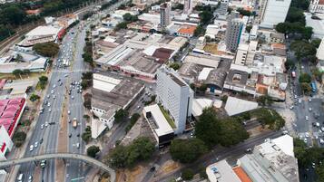 An aerial view of a cityscape with a prominent modern building, a busy intersection, and surrounding urban infrastructure.