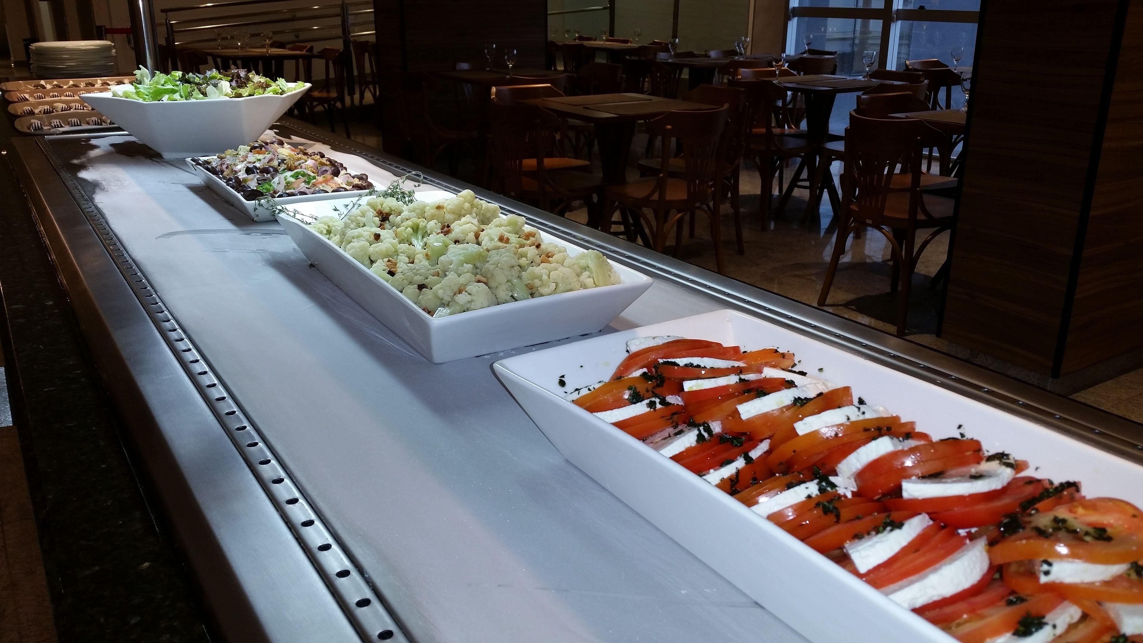 A buffet with various dishes including salads, cauliflower, and tomato and mozzarella.