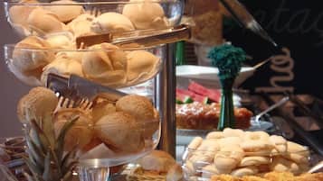 A buffet with various food items including bread, pastries, and fruits.